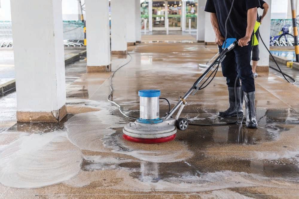 Floor scrubbing machine cleaning a walkway